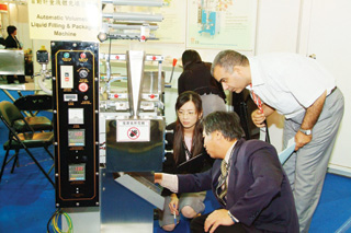 A foreign buyer inspects a Taiwan-made automatic liquid filling and packaging machine.