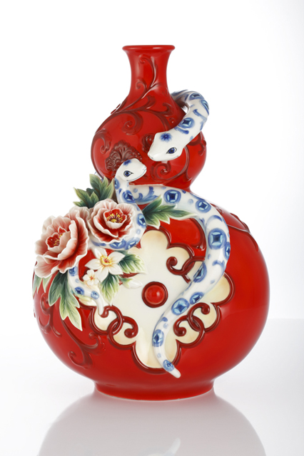 A carved vase from the Franz Collection features a red body with two snakes and peonies. 