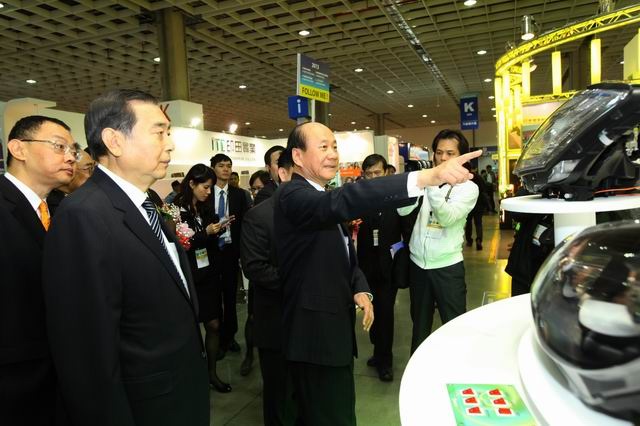 Economics Minister Chang Chia-juch (front right) points to the latest auto lamps, accompanied by TAITRA chairman Wang Chih-kang (front left).