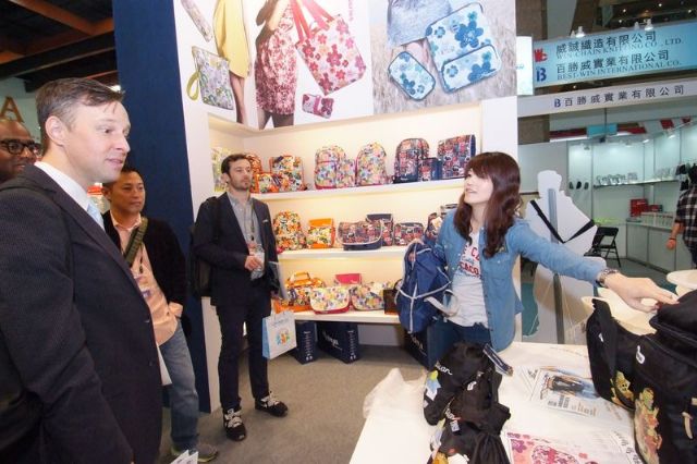 A booth showcasing various fashionable bags and knapsacks attracts foreign buyers.