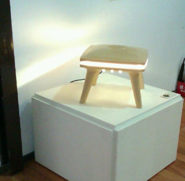 Seating and lighting functionality combine in this wooden stool by embedding a light source in the seat structure.
