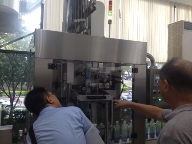 Visitors look at Benison’s high-speed label sleeaving machine at the venue.