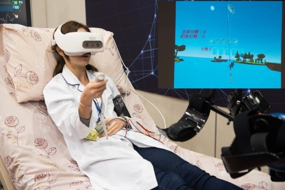記者會上示範VR虛擬遊戲協助重症病患手部復健。 黃啟銘/攝影、合圖。