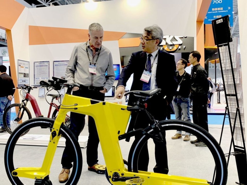 自行車中心總經理梁志鴻（右）向參觀者解說碳纖維板殼車架與無花鼓輪組設計成果。 CHC／提供